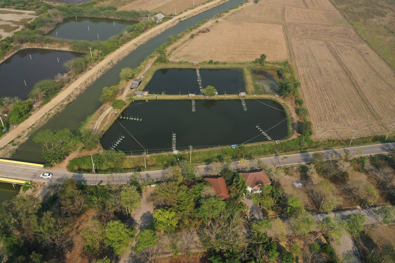 Aerial shot of agricultural landscape in Phetchaburi, Thailand, featuring ponds and fields.